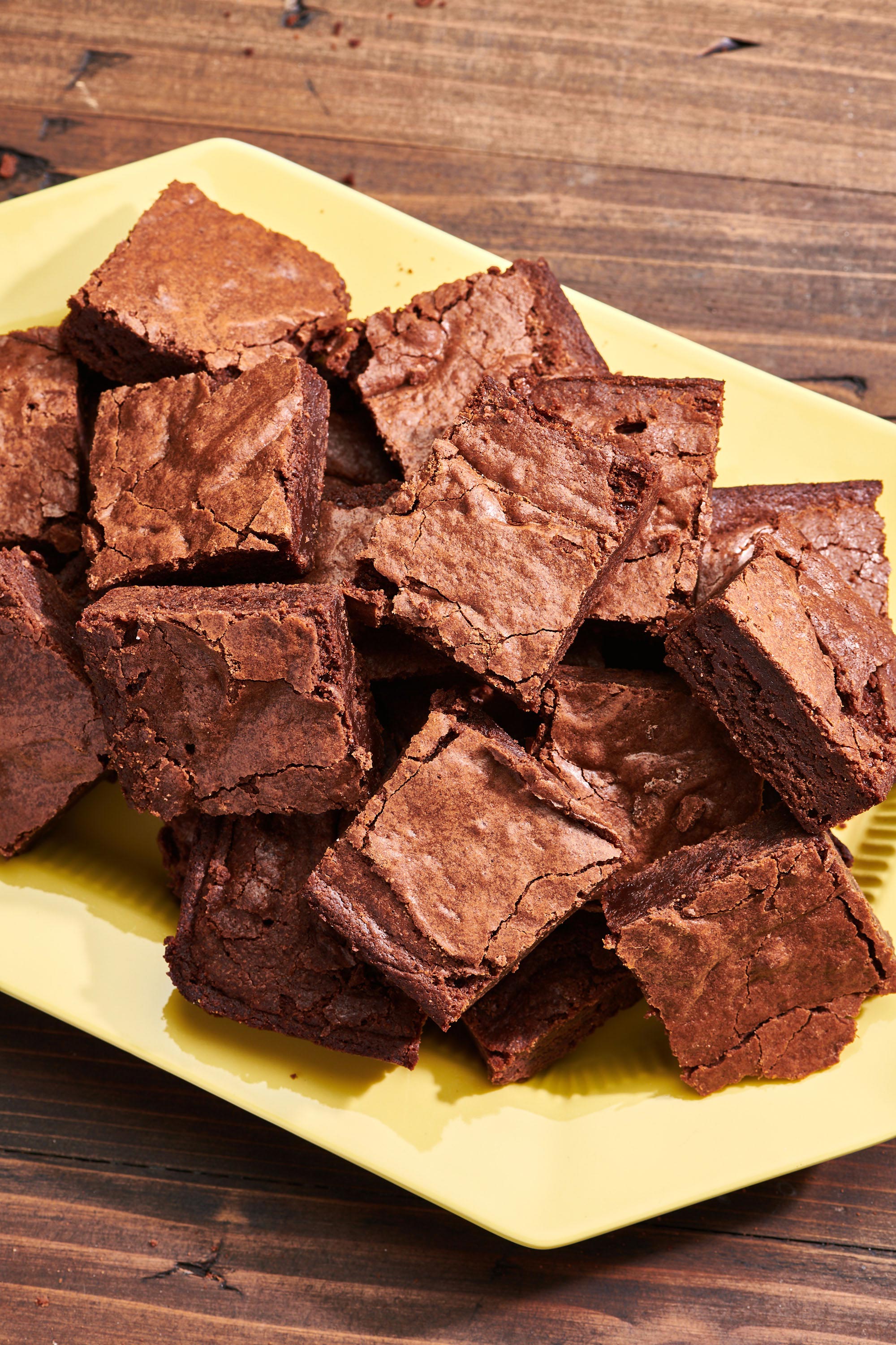 Fudgy Brownies piled on a light yellow plate.