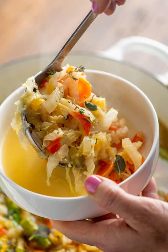 Ladle scooping Simple Vegetable Soup into a bowl.