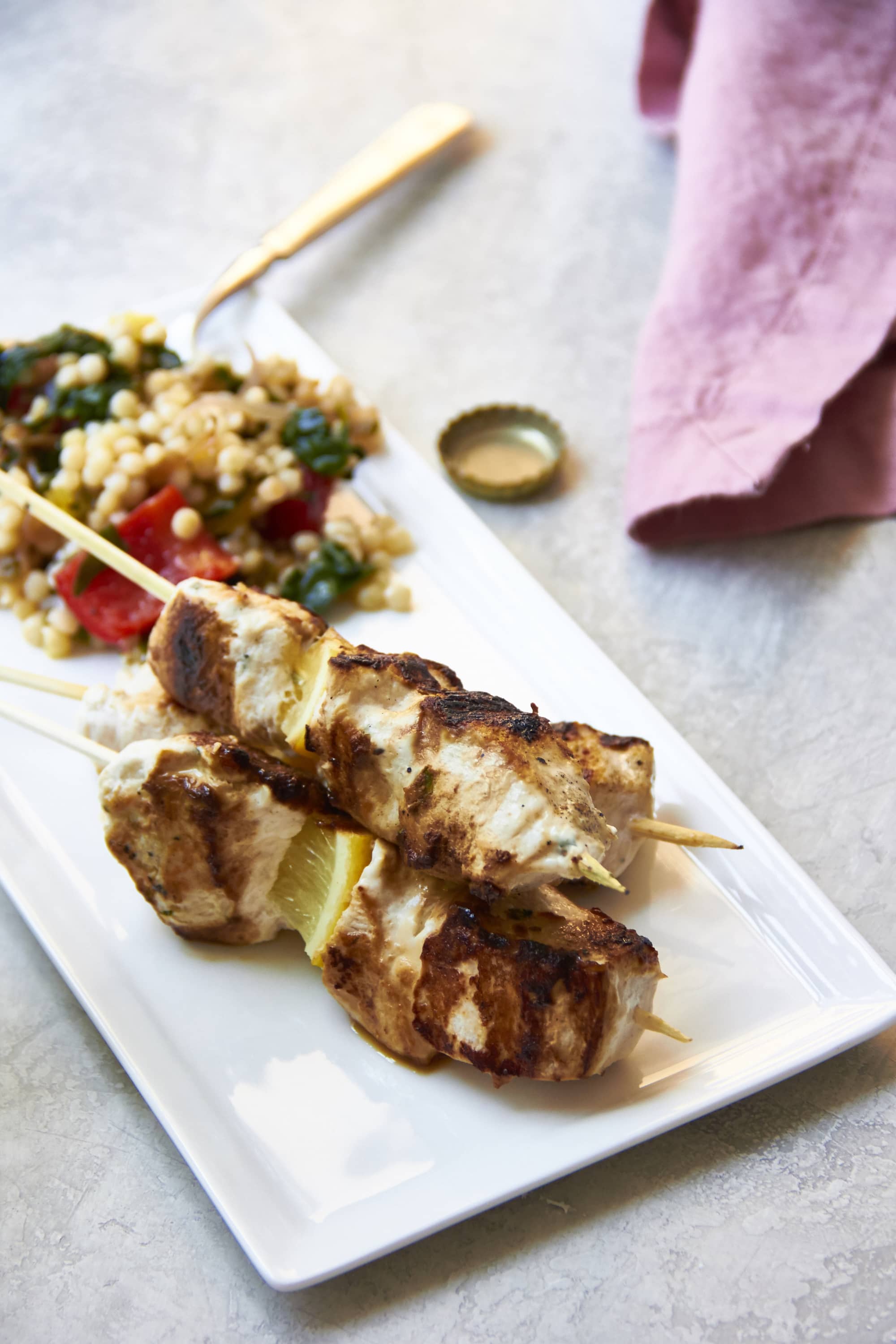 Two Marinated Chicken Kebabs on a plate with a grain salad.