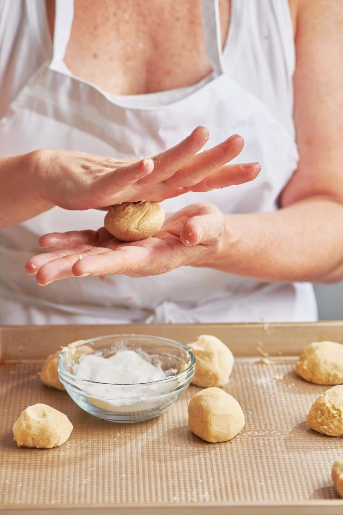 Woman rolling balls of Sugar Cookie dough.