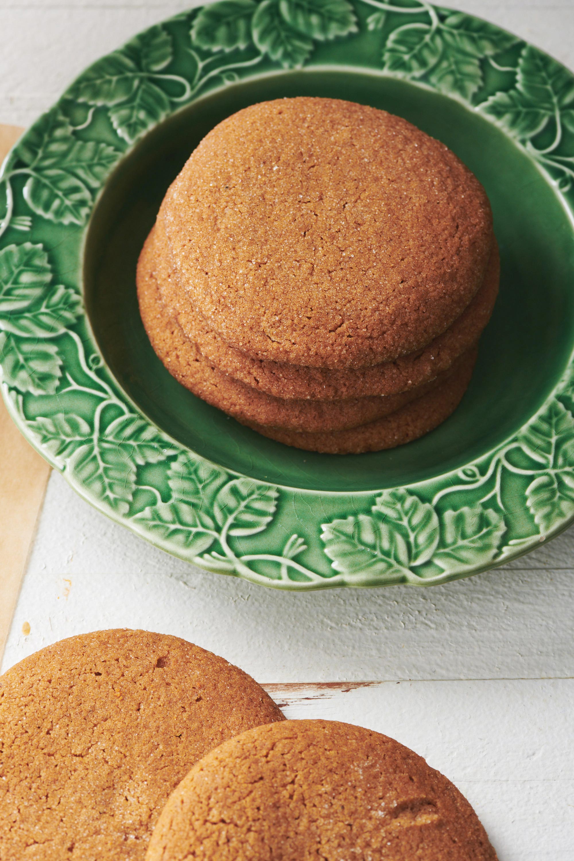 Gingersnaps stacked on a green plate.