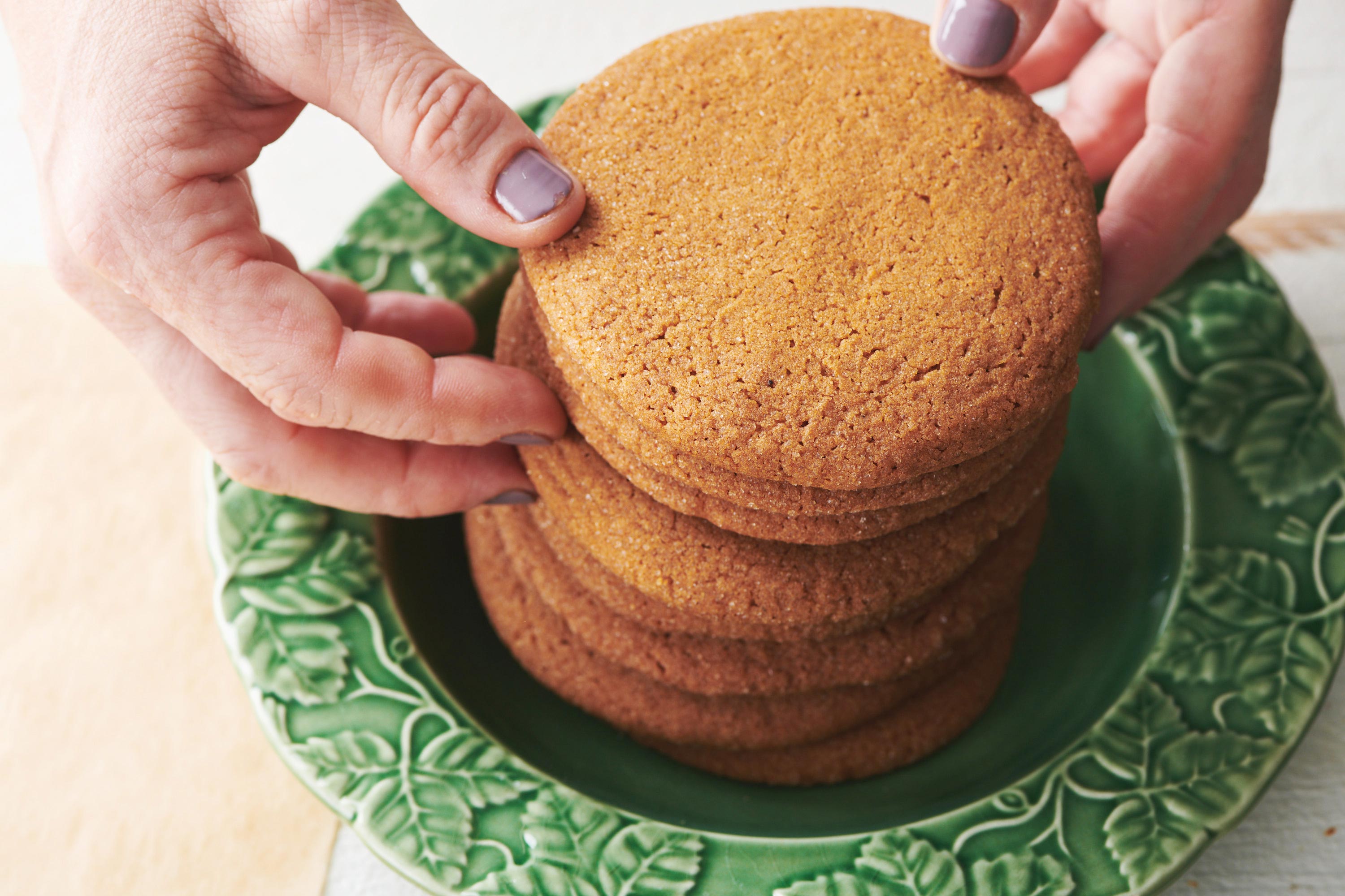 Woman stacking Gingersnaps high on a green plate.