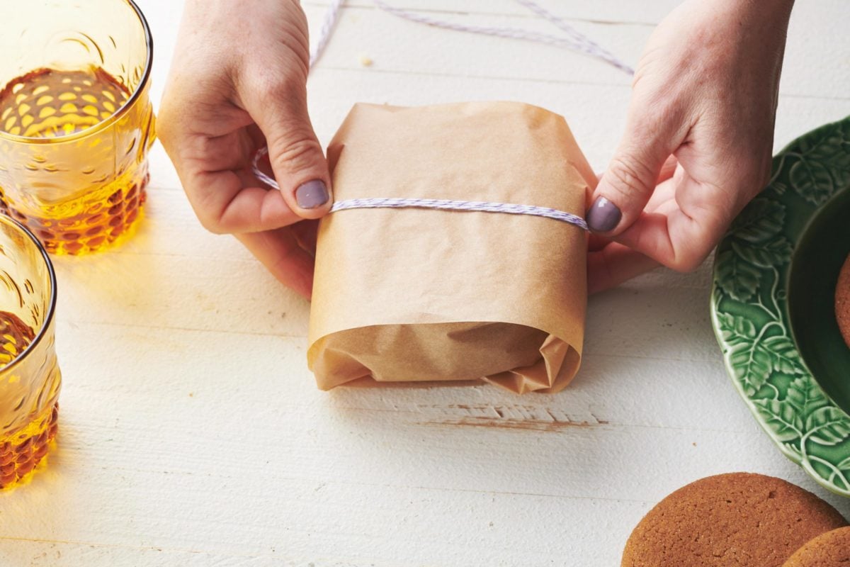 Woman tying twine around Gingersnaps in parchment paper.