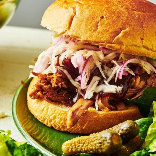 BBQ pulled pork sandwich with cole slaw on green plate.