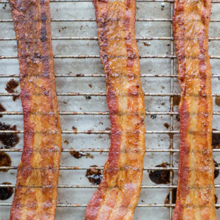 Cooked bacon on wire rack and baking sheet.