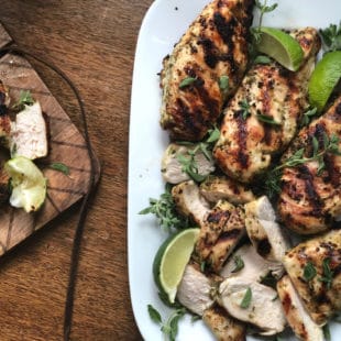 Herbed Chicken on a dish with lime wedges and herbs.