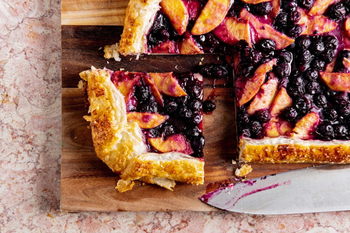 Blueberry and peach crostada with a piece cut out.