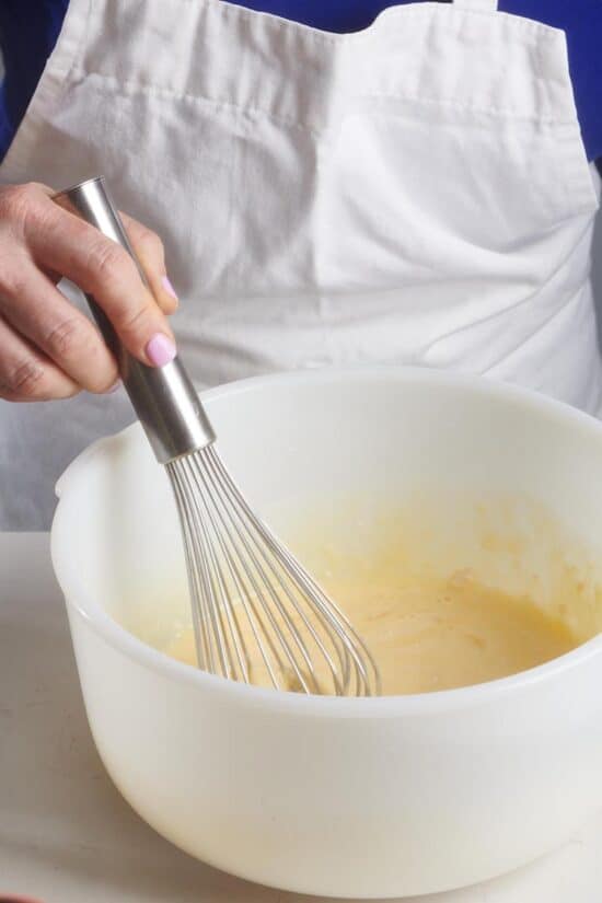 Woman whisking a bowl of popover batter.