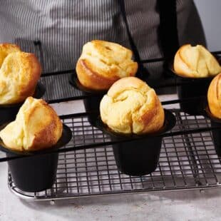Six popovers in popover tins on a wire rack.