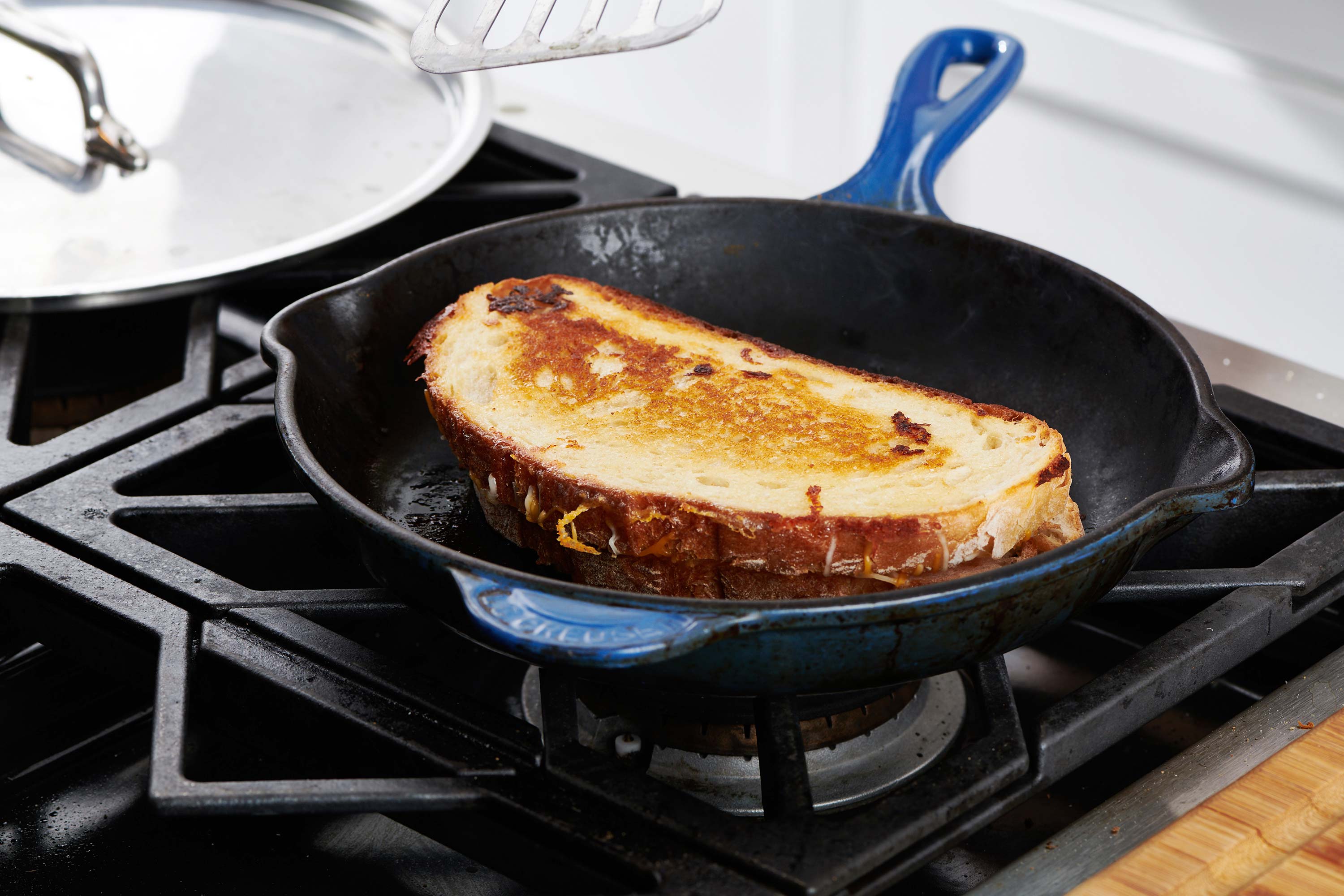 Grilled cheese sandwich in a skillet on the stove.