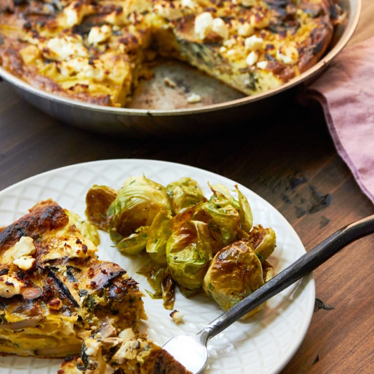 Mushroom, Caramelized Onion and Feta Frittata on a plate with brussels sprouts.