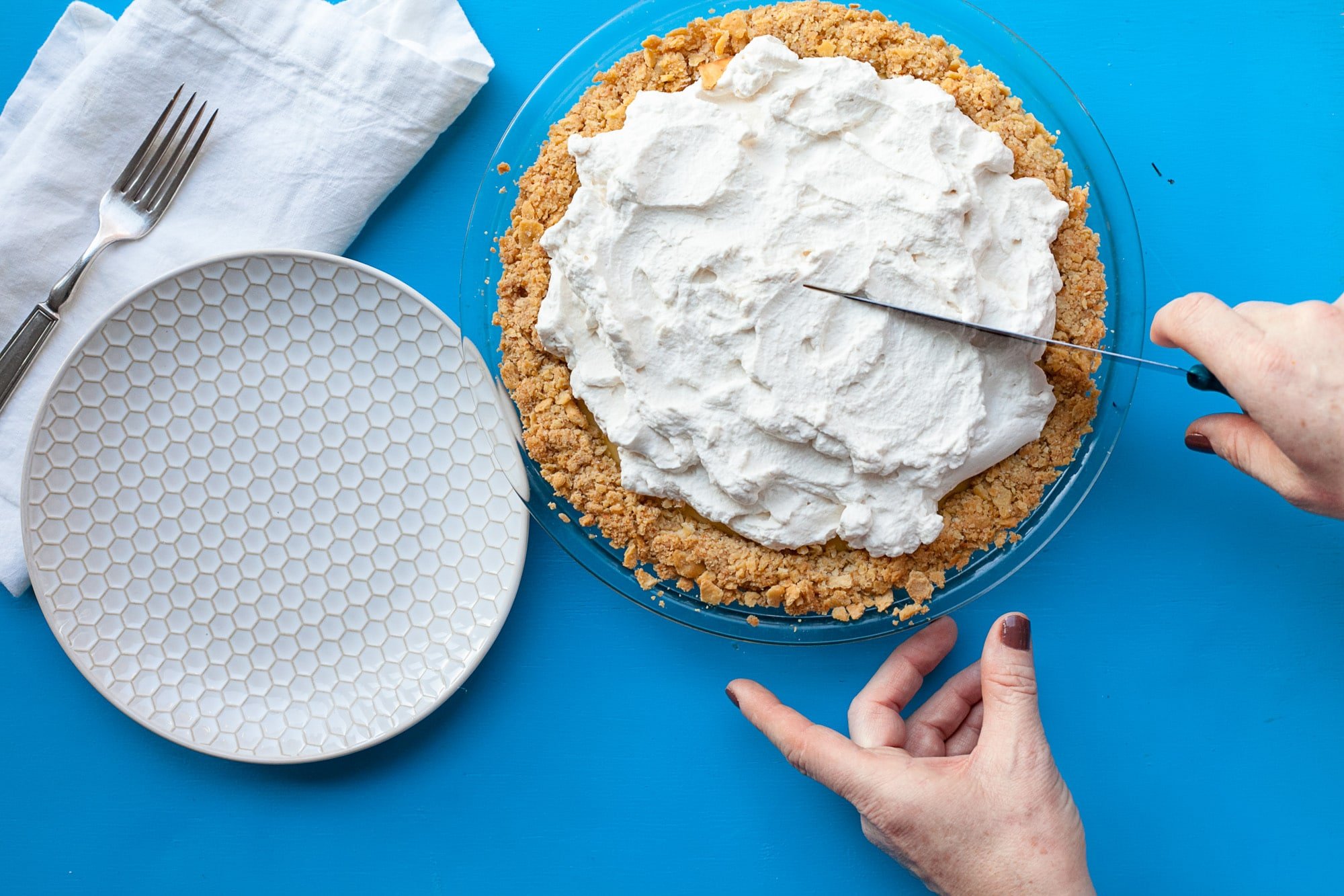 Woman slicing Atlantic Beach Pie in pie plate next to empty plate.