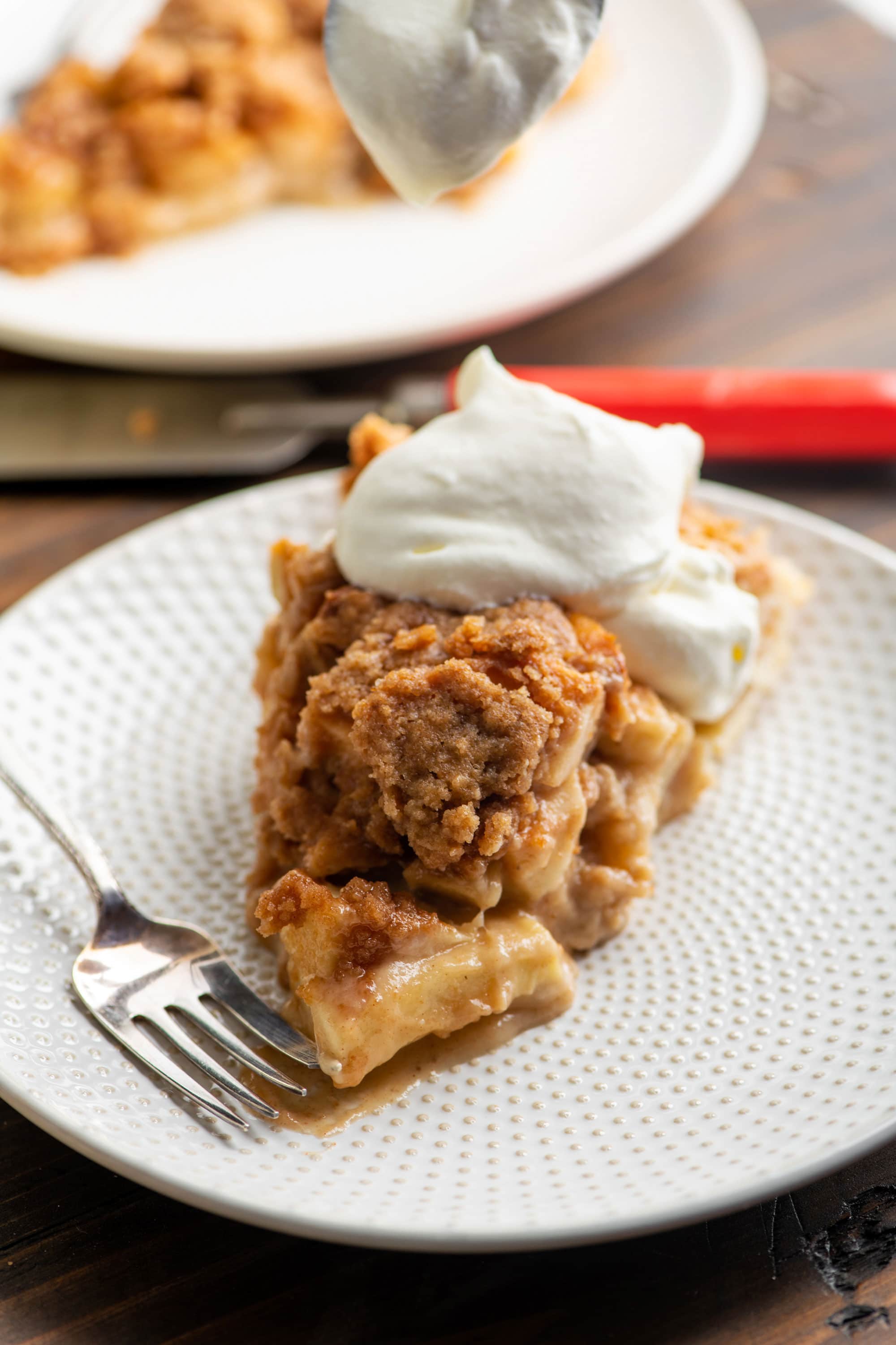 Slice of Streusel Apple Pie topped with whipped cream.