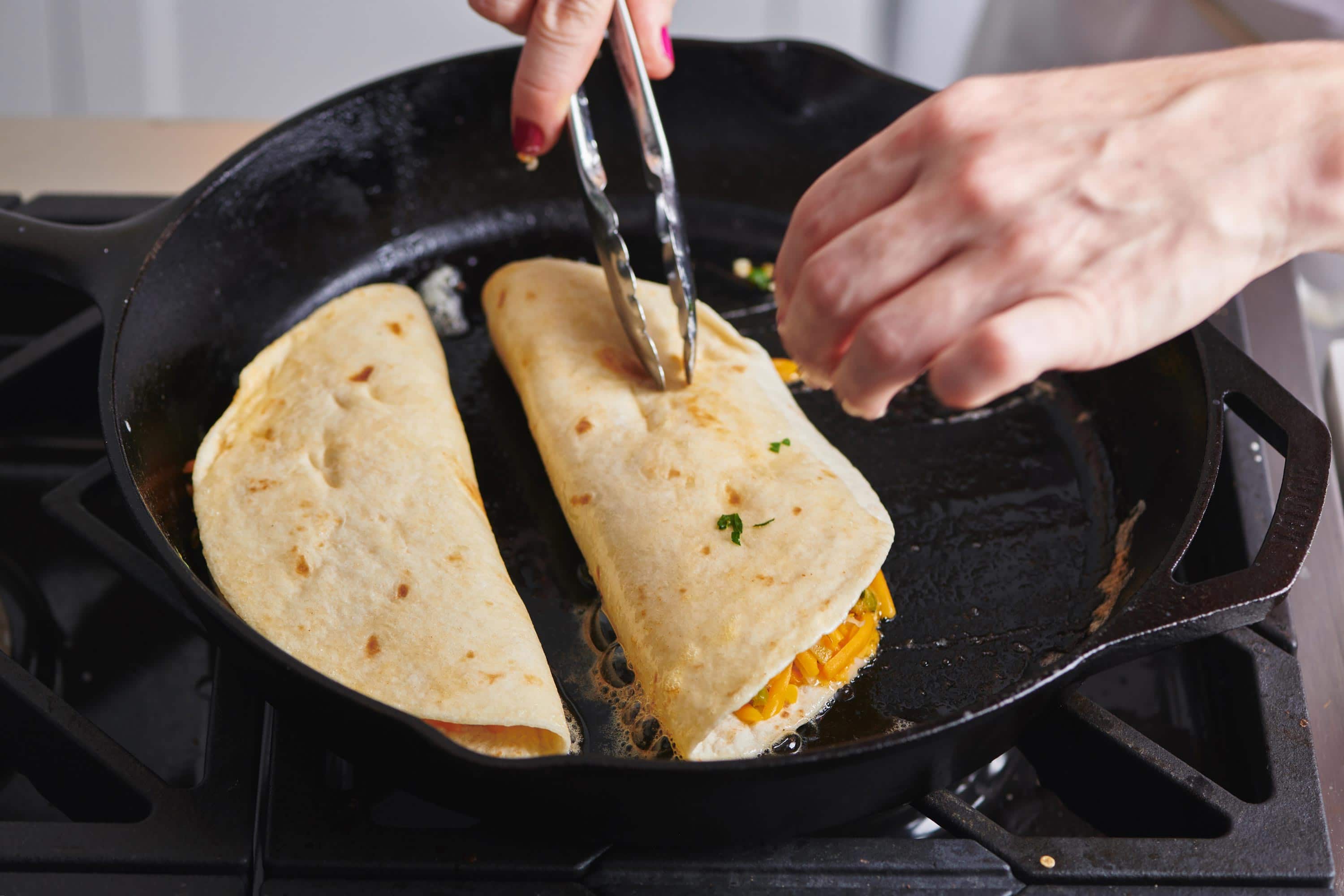 Woman cooking quesadillas in a cast iron skillet.