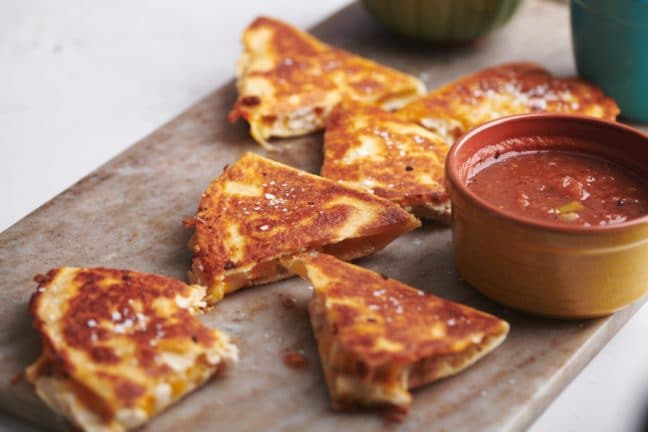 Cut Rotisserie Chicken and Cheese Quesadillas on a board with bowls of dip.