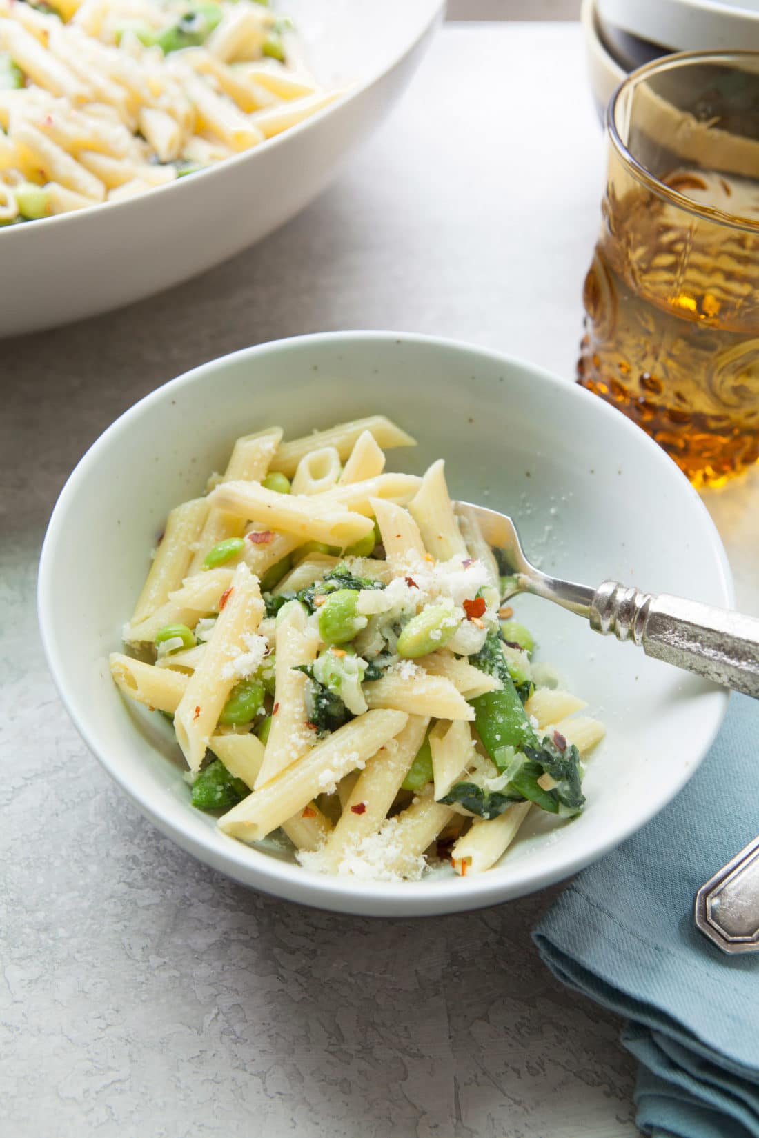 Small bowl of Pasta with Ramps, Edamame, and Snap Peas in a Light Parmesan Cream Sauce.