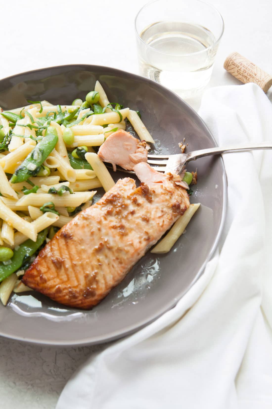 Plate of Fish next to Pasta with Ramps, Edamame, and Peas in a Parmesan Cream Sauce.