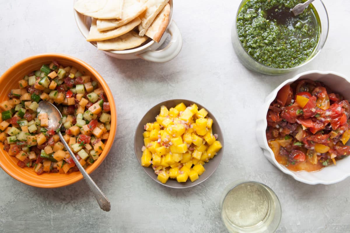 Bowl of Citrusy Mango Ginger Salsa on a table with other foods.