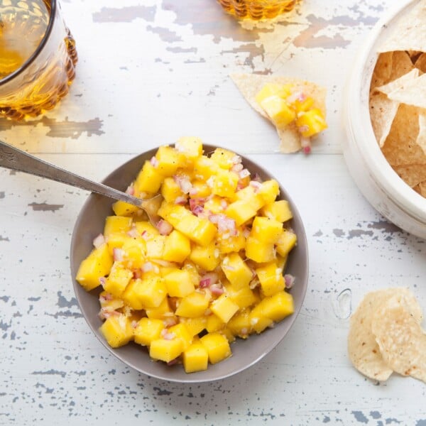 Table set with chips and a bowl of Citrusy Mango Ginger Salsa.