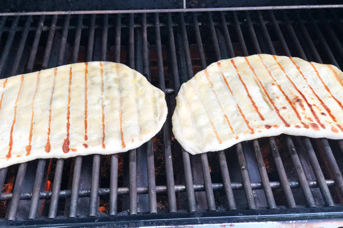 Two pizza crusts on the grill.