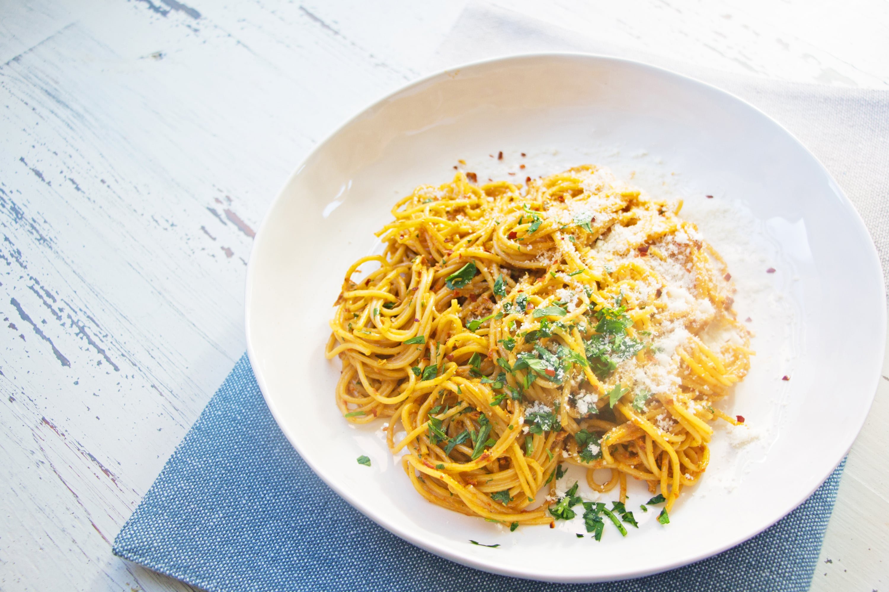 Pasta with Creamy Sundried Tomato and Scallion Sauce on white plate with blue napkin.