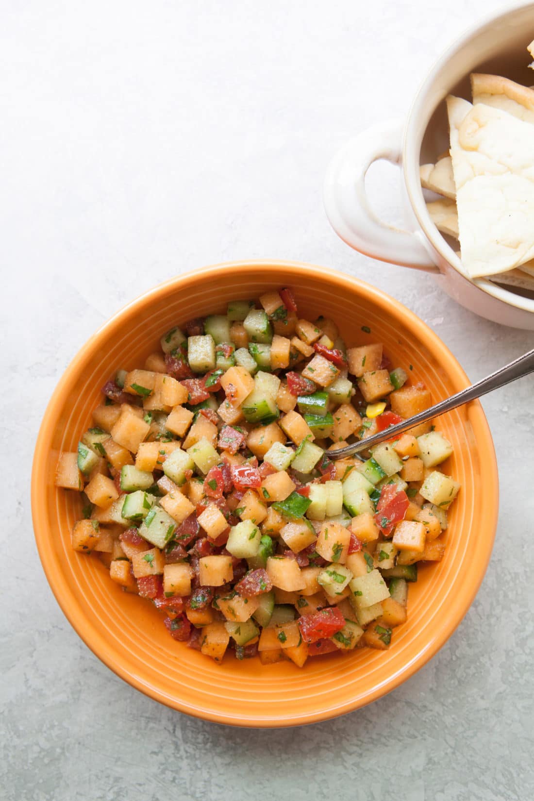 Spoon in a bowl of Corn, Cucumber and Cantaloupe Salsa.