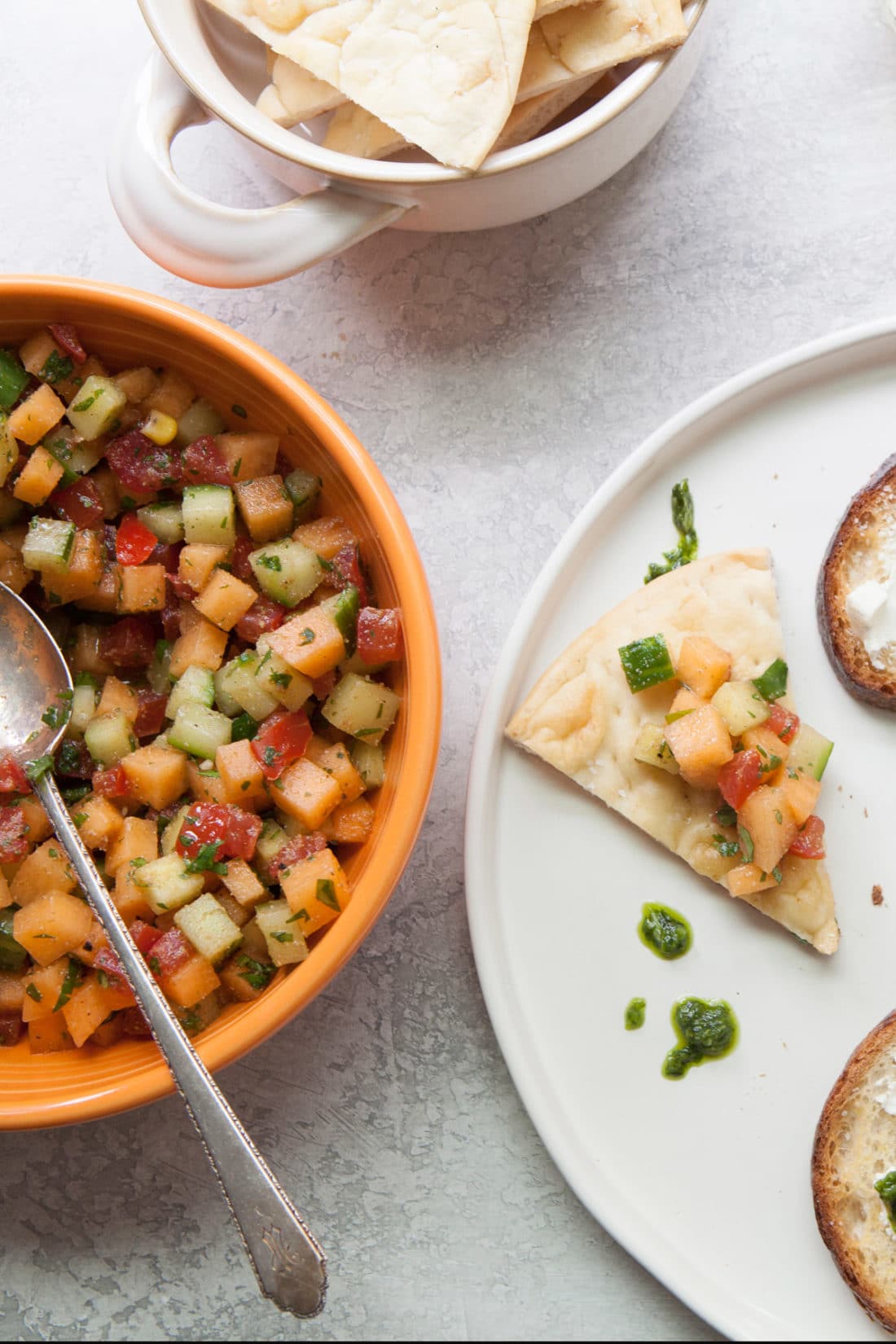 Chip topped with Corn, Cucumber and Cantaloupe Salsa on a plate.