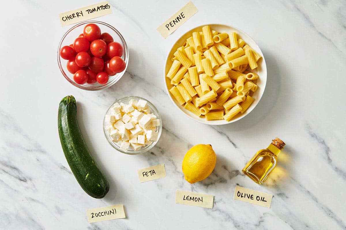 Ingredients for Vegetarian Greek Pasta on white marble table.
