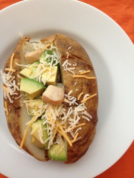 Baked potato topped with chicken, avocado, and cheese.