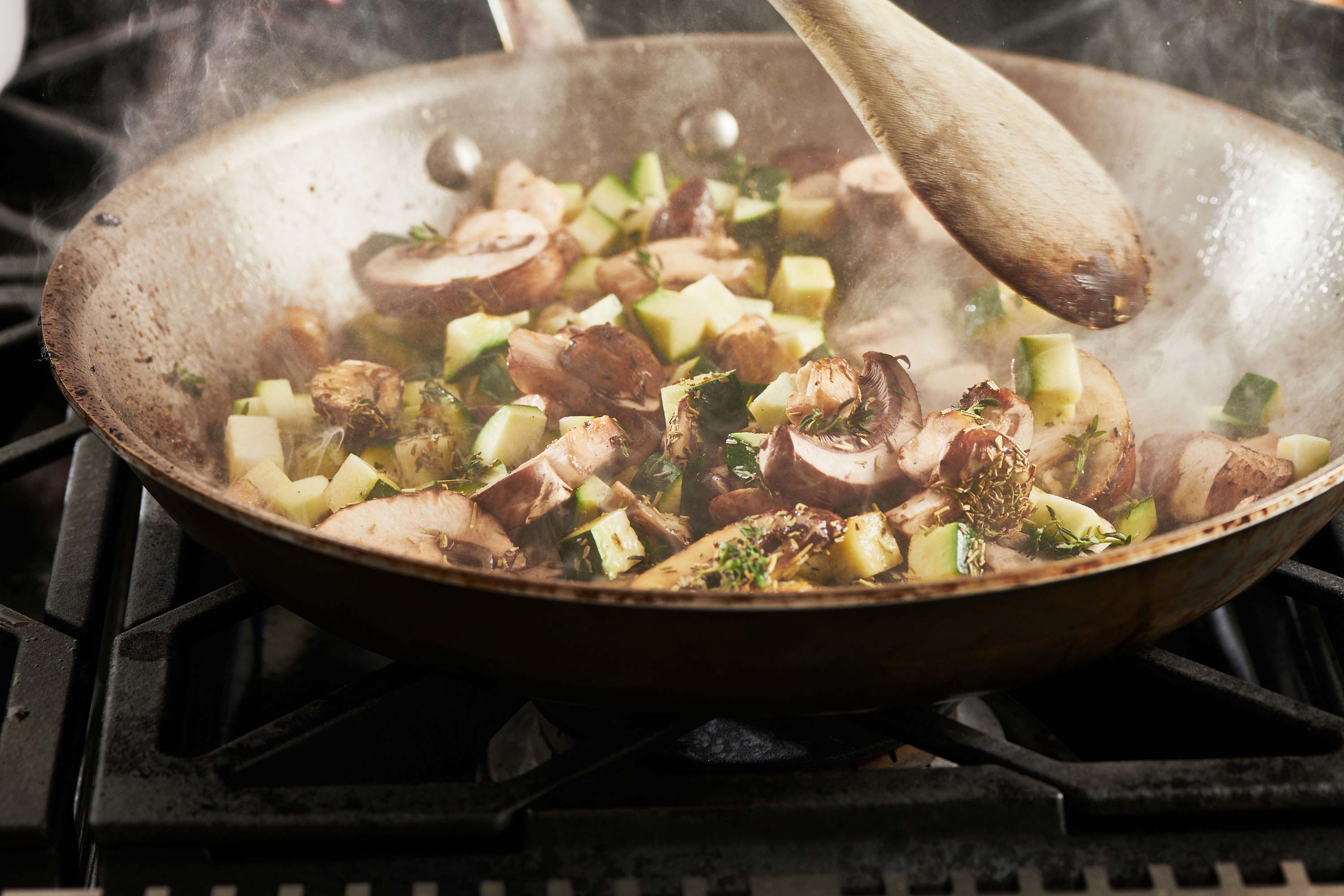 Zucchini and mushrooms sauteing in skillet.