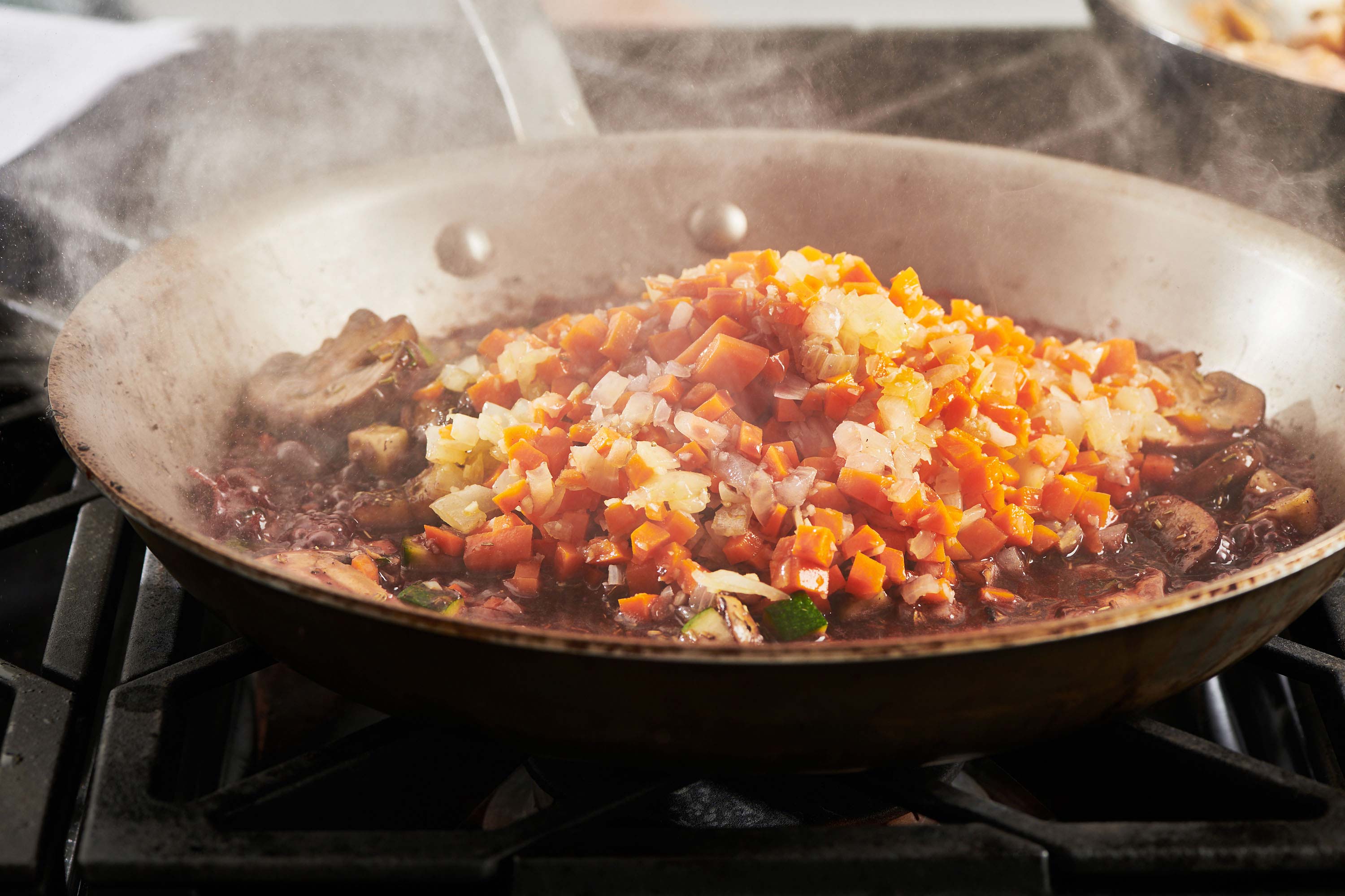 Steaming skillet of chopped vegetables.
