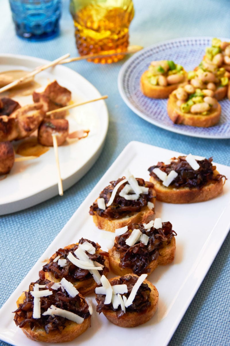 Radicchio and Endive Crostini with Goat Cheese and Balsamic Glaze on a table with other foods.