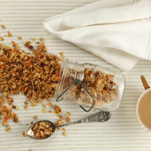 Homemade Granola spilling out of a jar onto a table.