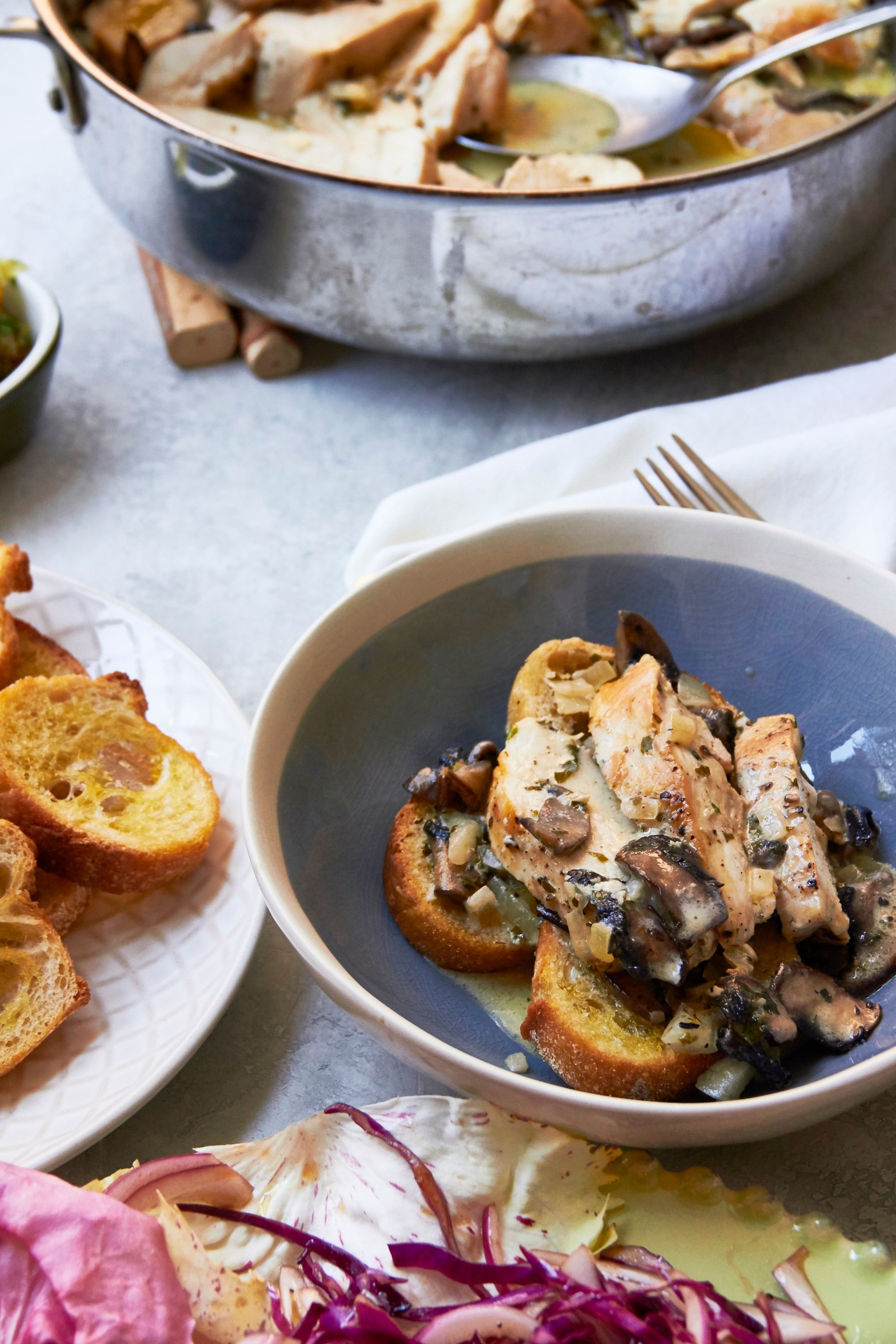 Chicken with Mushrooms in Cream Sauce over toasts in a blue bowl.