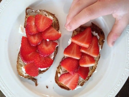 Person grabbing a ricotta berry breakfast crostini.