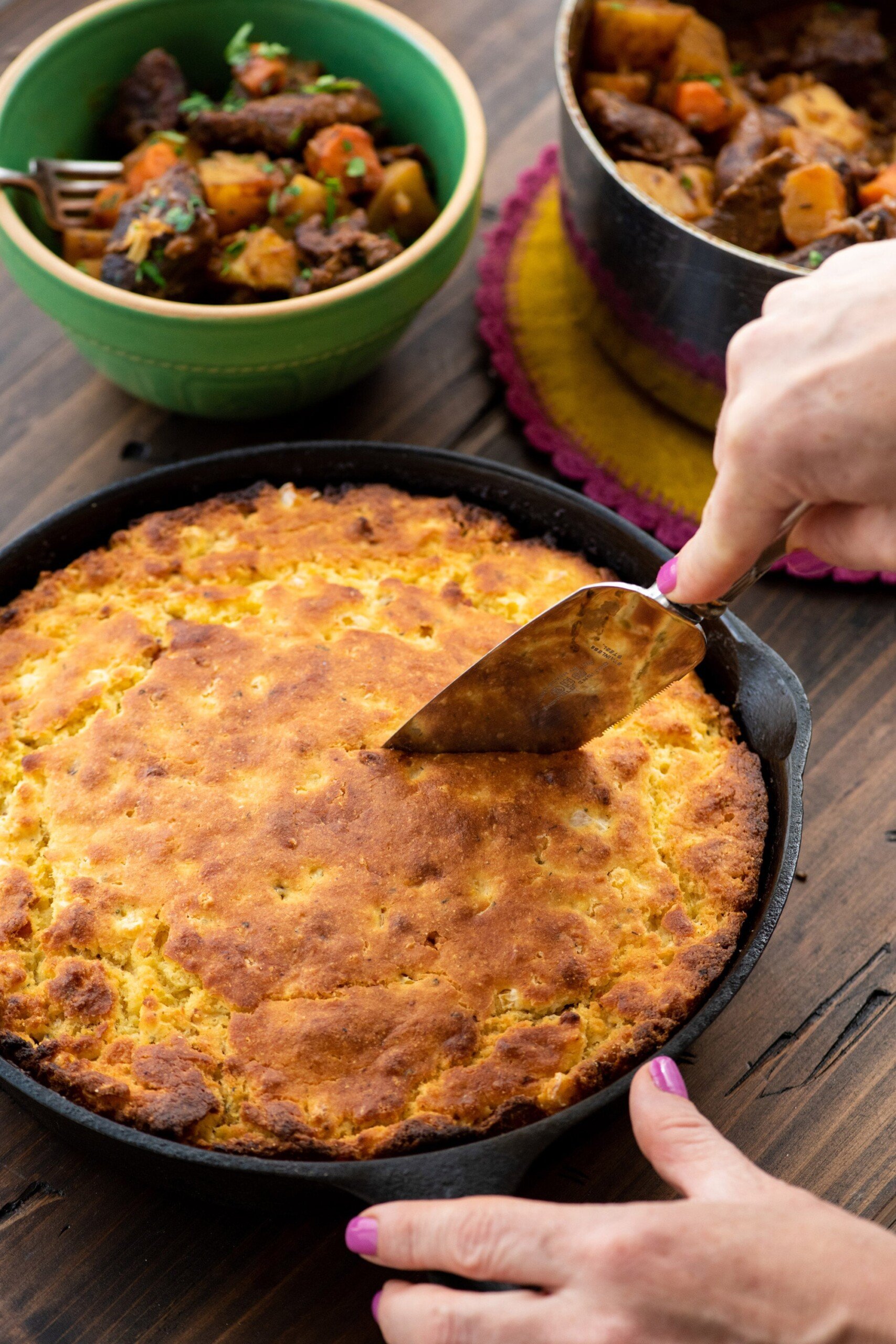 Woman slicing a piece of Bacon, Fresh Corn, and Oregano Cornbread.