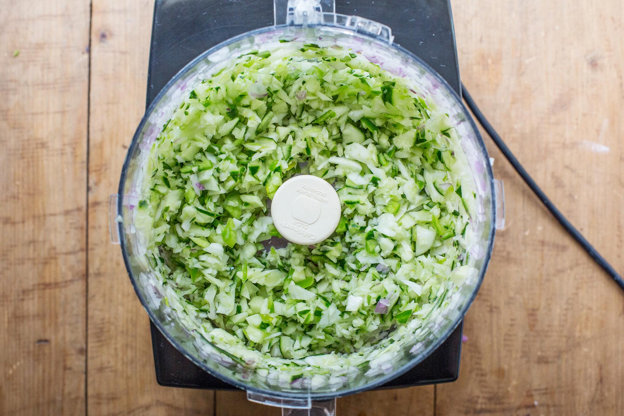 Chopped cucumber in the bowl of a food processor.