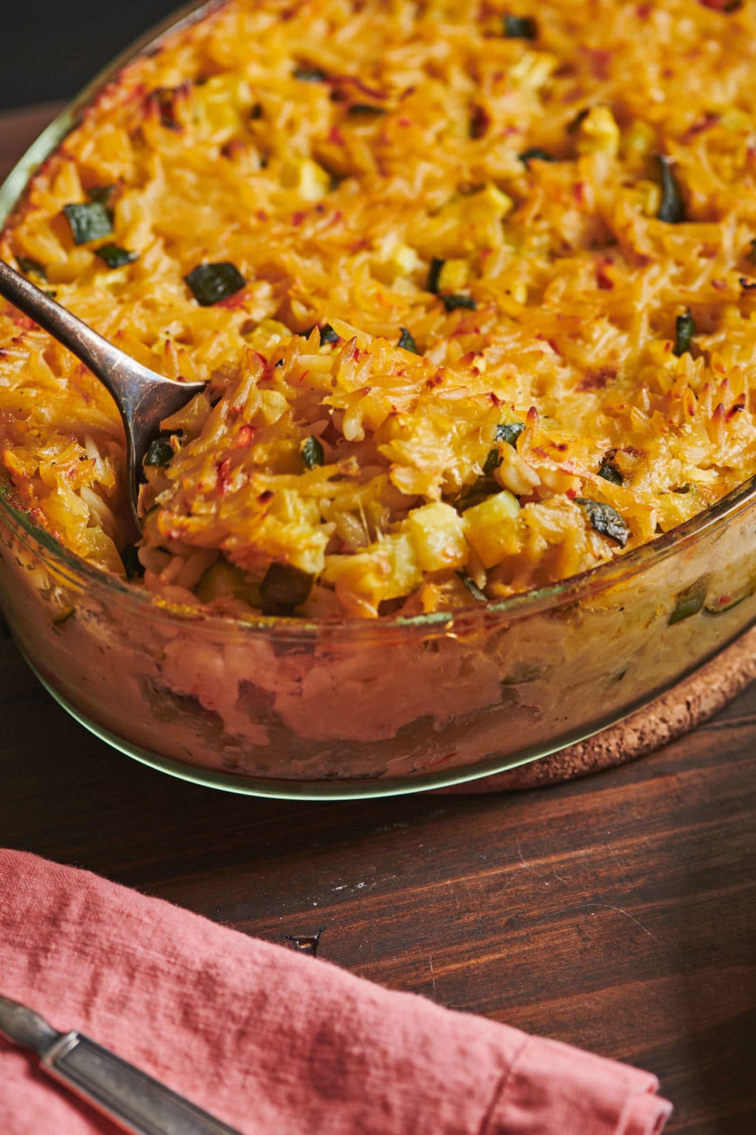 Spoon in a glass dish of Cheesy Orzo Casserole.