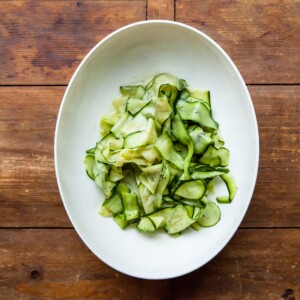 White serving plate of Zucchini Ribbon Salad on a wooden table.