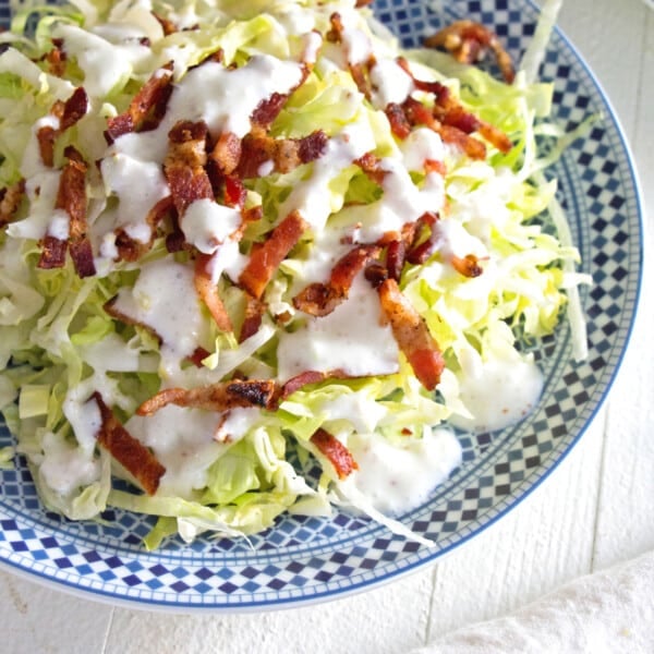 Slivered Wedge Salad with Buttermilk Dressing and Bacon on a blue and white plate.
