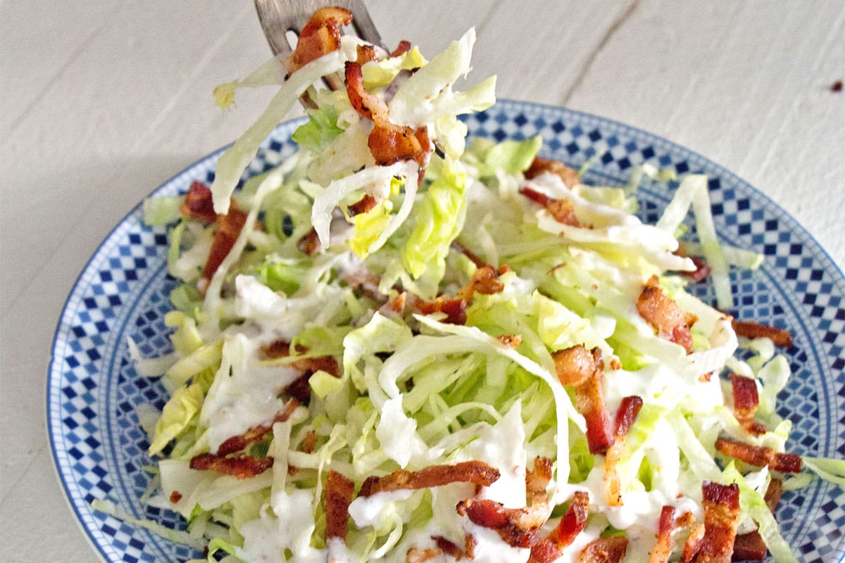 Serving wedge salad with buttermilk dressing in bowl with fork.