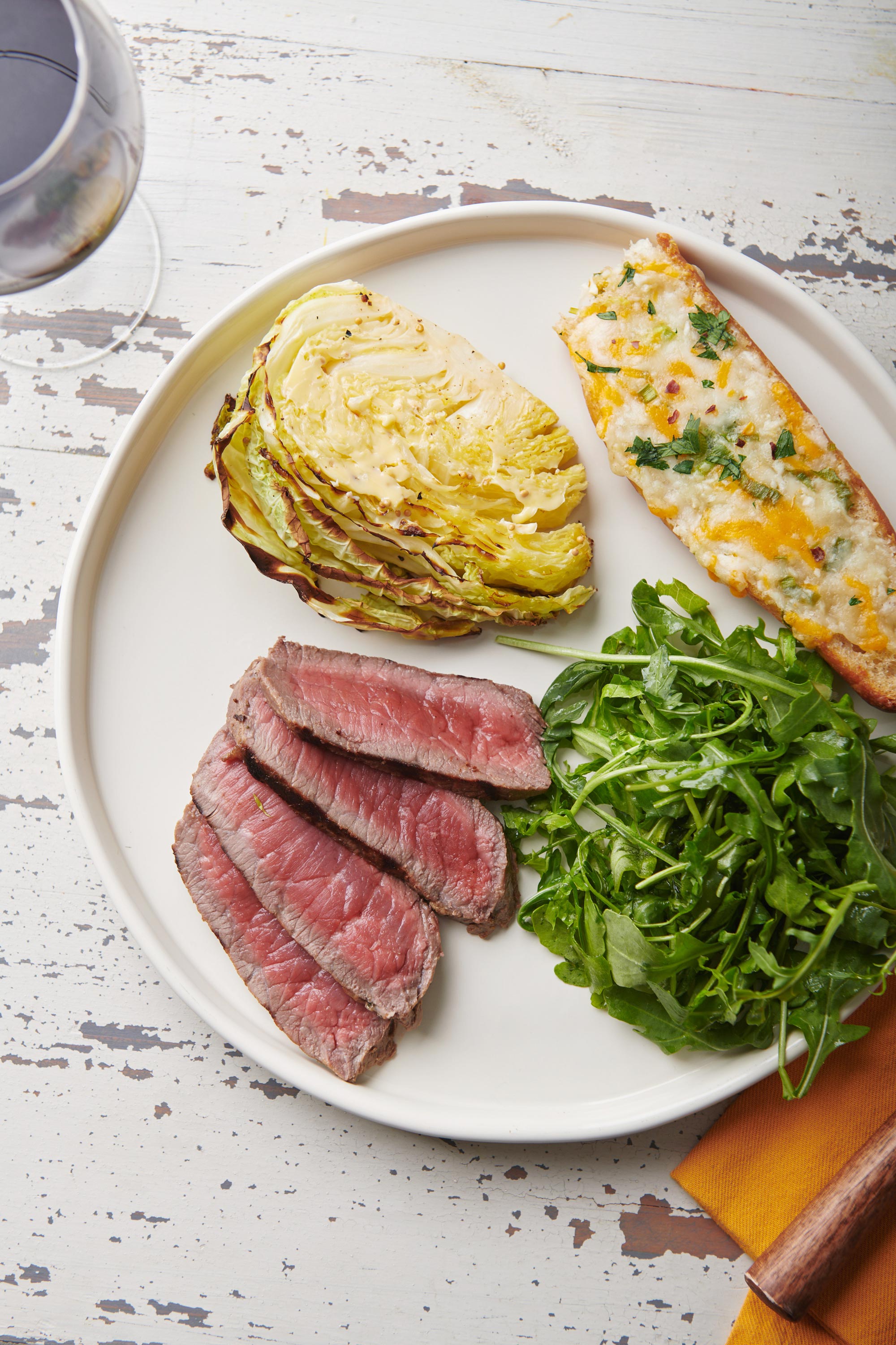 Slices of Mustard Marinated London Broil on a plate with greens and bread.