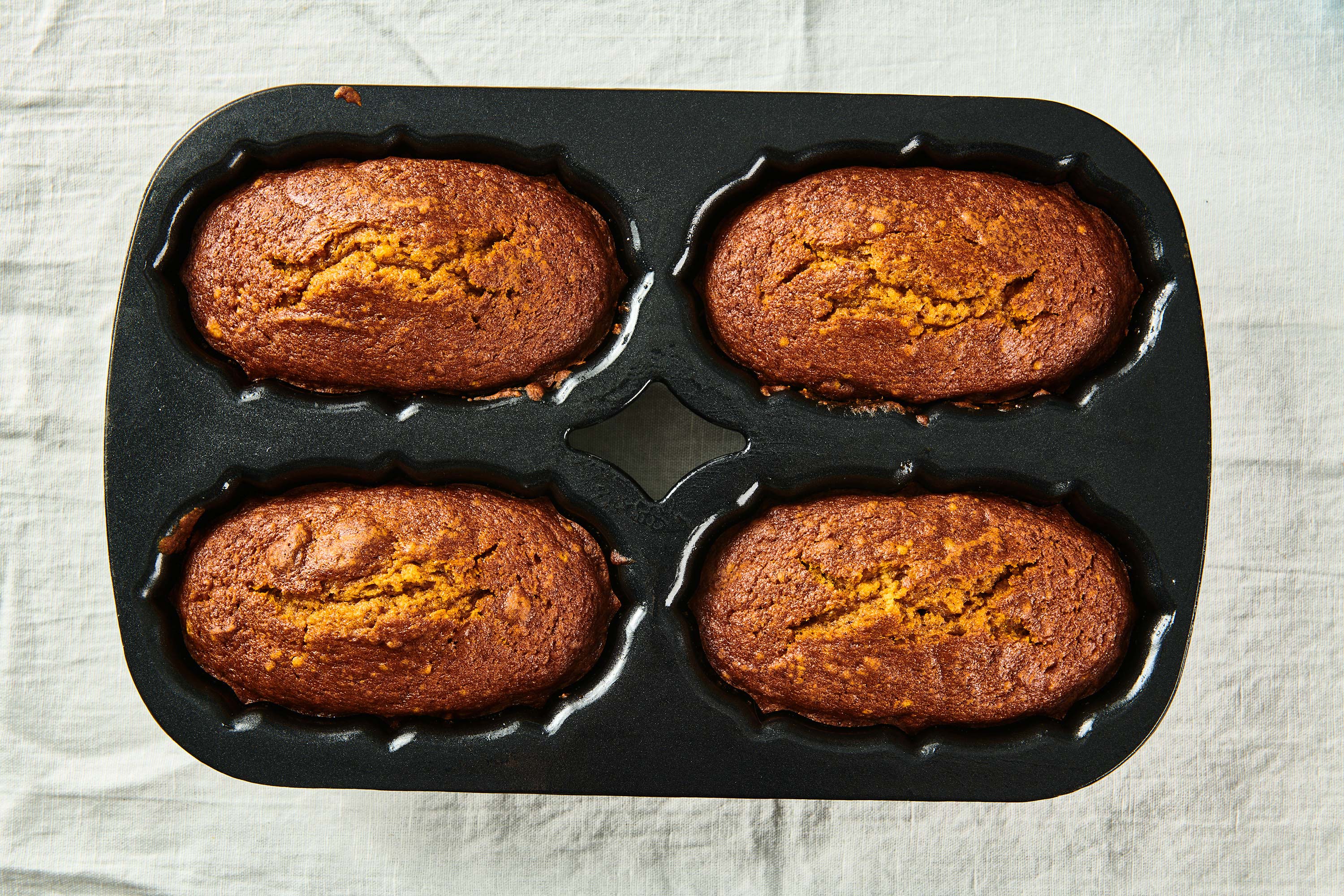 4 loaf pan with baked pumpkin breads in it.