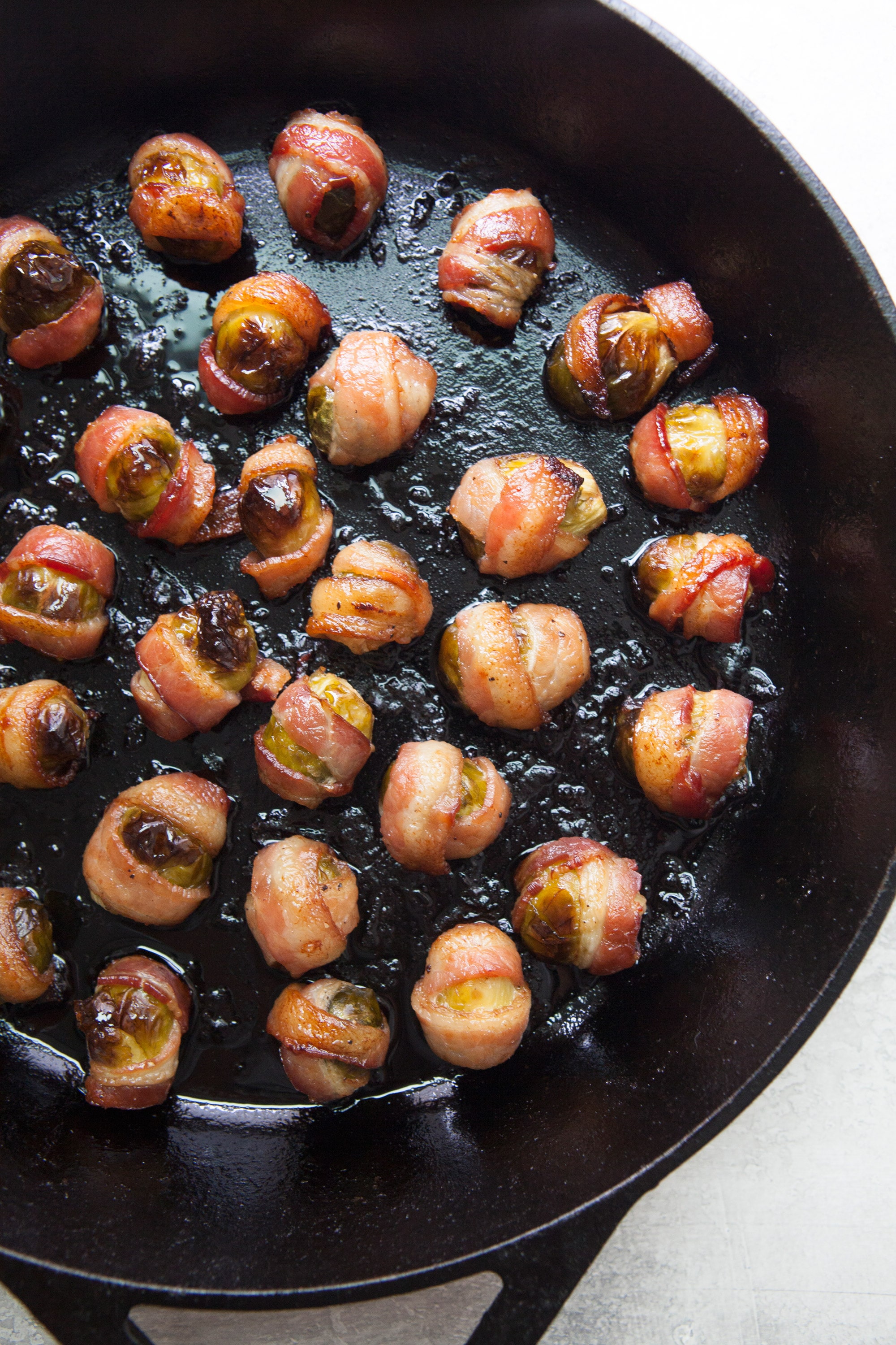 Bacon Wrapped Brussels Sprouts in a cast iron skillet.