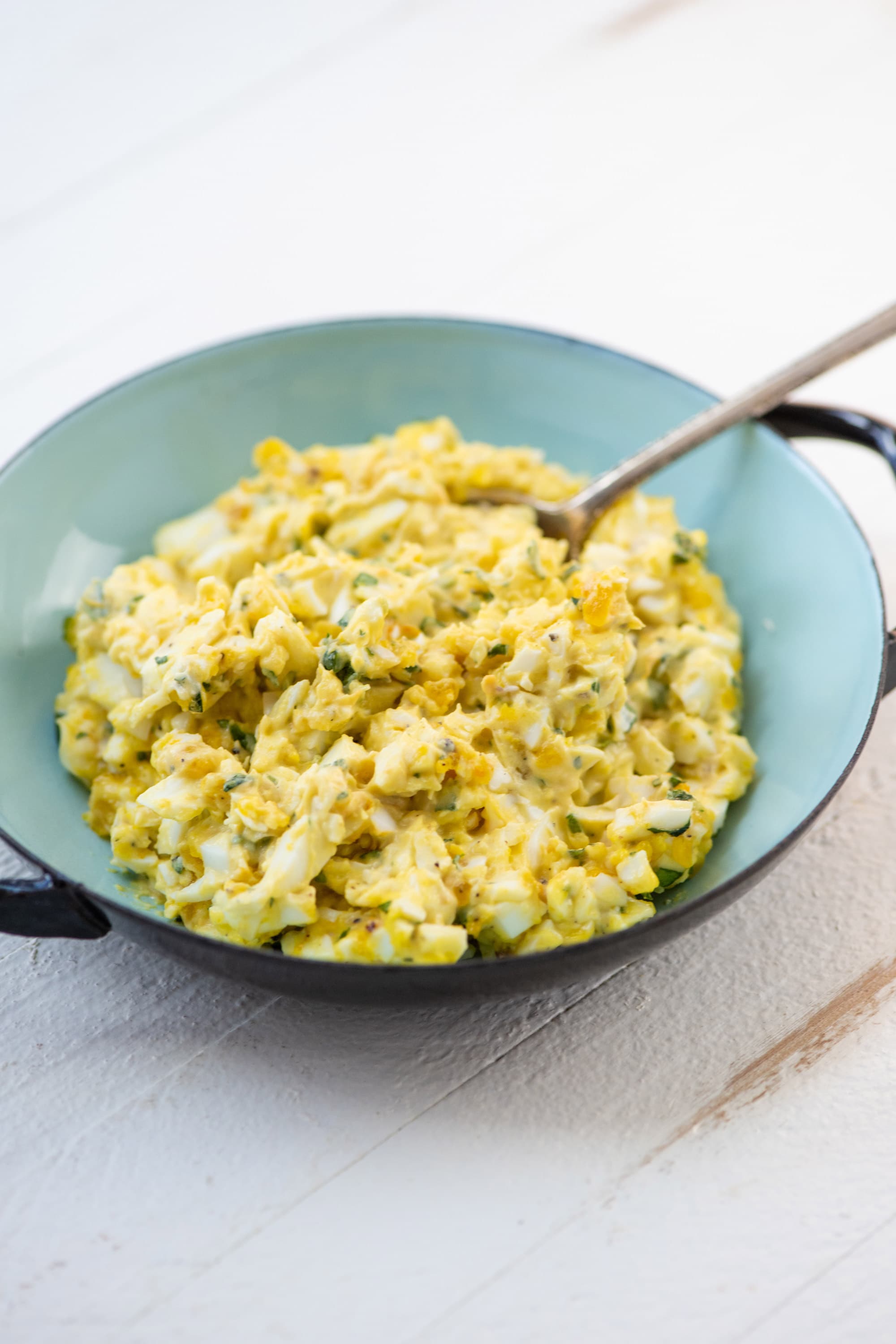 A blue bowl with orange basil egg salad.