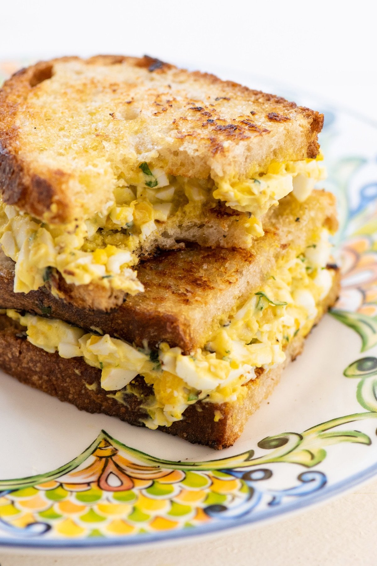 An egg salad sandwich with a bite taken out of it.