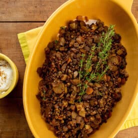 Yellow serving dish filled with lentil, carrots, and dried apricots.