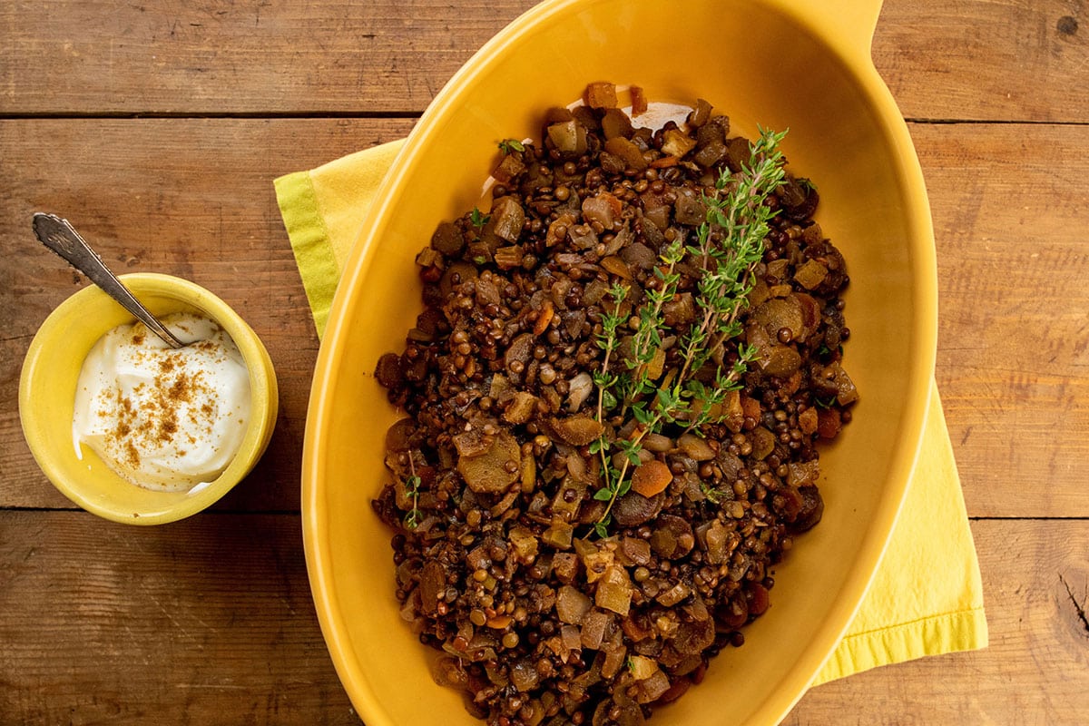 Yellow serving dish filled with lentil, carrots, and dried apricots.