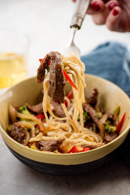 Fork grabbing a bite of Spicy Stir Fried Beef and Vegetables with noodles.