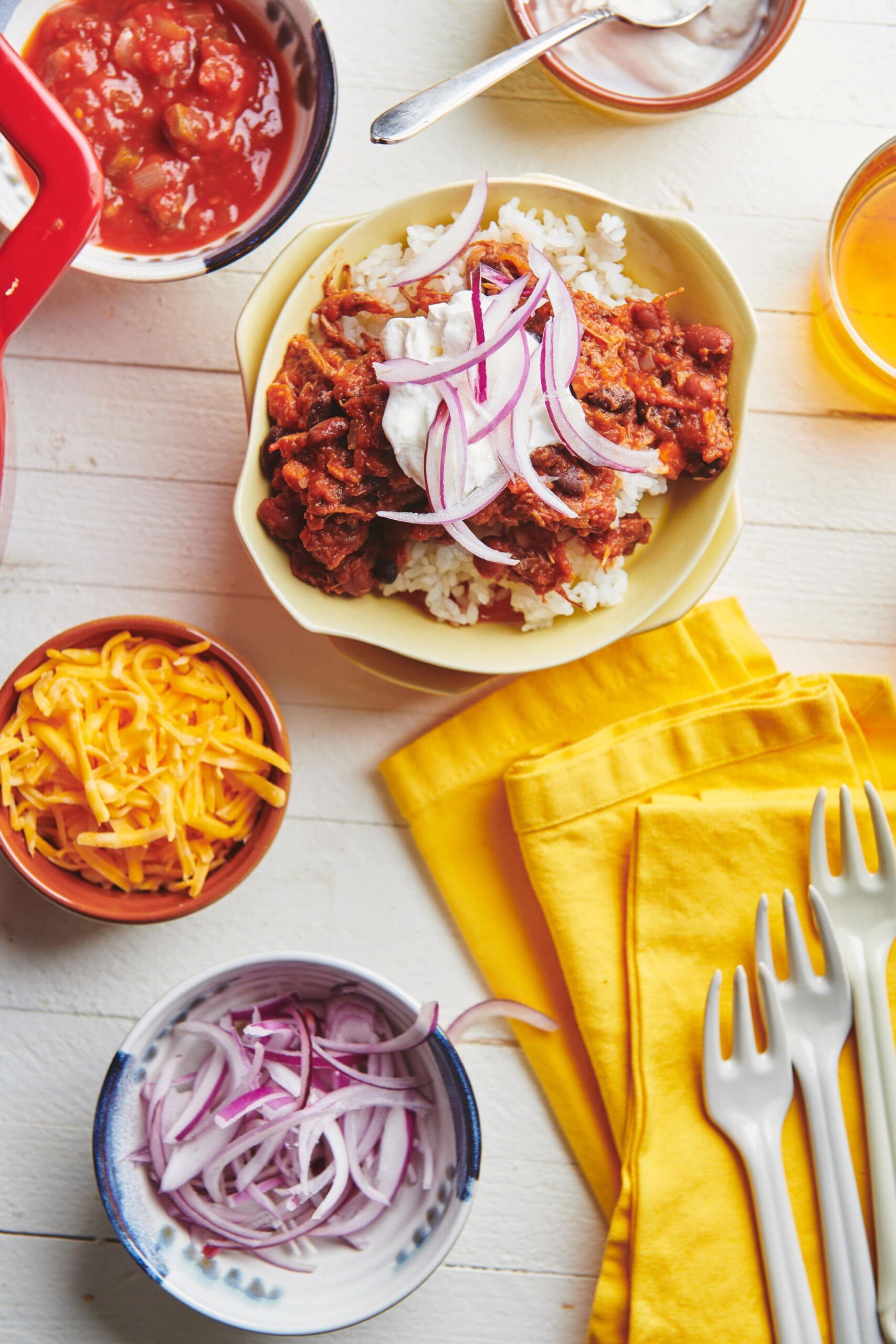 Bowl of Barbacoa Beef Chili over rice topped with red onions and sour cream.